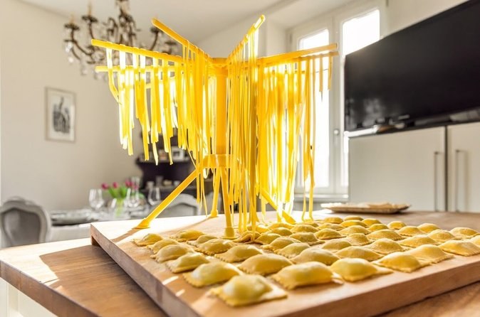 Fresh pasta hanging to dry above a tray of filled ravioli