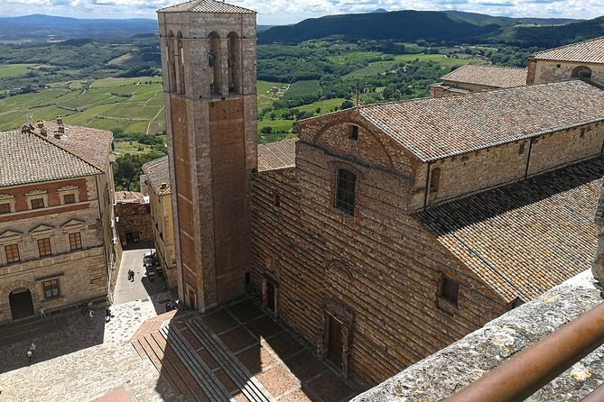 A bell tower rising over Montepulciano's roofs, with vineyards and hills behind