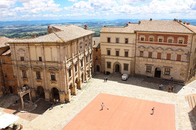 Piazza Grande from above, its brick pavement lying empty between the palace fronts