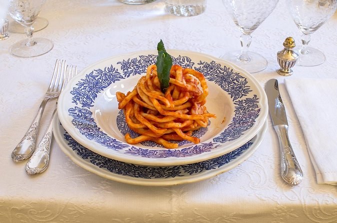 Pici, the thick hand-rolled pasta of this corner of Tuscany, in tomato sauce on a blue-and-white plate
