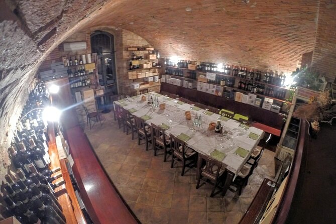 A long tasting table laid under a brick vault, bottles on the shelves behind